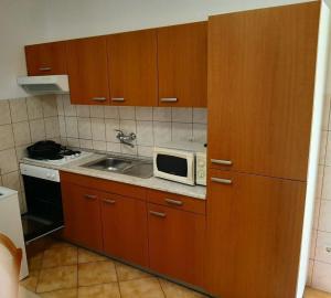 a kitchen with wooden cabinets and a microwave at Apartmani Šegedin in Korčula