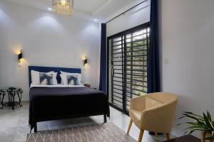 a bedroom with a bed and a chair and a window at Villa Umy in Ngaparou