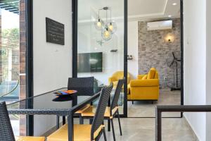 une salle à manger avec une table, des chaises et une chaise jaune dans l'établissement Villa Umy, à Ngaparou