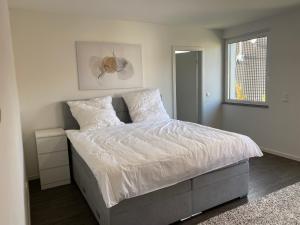 um quarto com uma cama com lençóis brancos e uma janela em Valley of Business Frankfurt-West - Penthouse Nº1 - Three-Bedroom em Hofheim