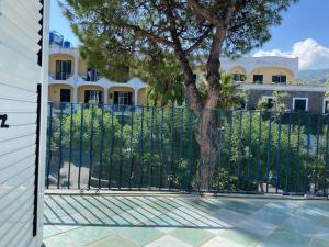 a fence with a tree in front of a house at Appartamento Casa di Sole Ischia in Ischia Town