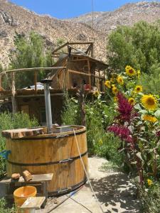 a wooden barrel in a garden with flowers at CAMPING GANIMEDES in Paihuano