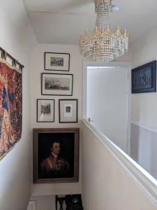 a chandelier hangs over a staircase with a painting of a woman at Craigmile Cottage in Fraserburgh