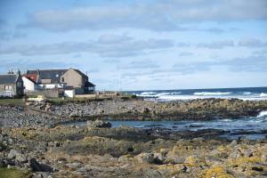 a house on the shore of a rocky beach at Craigmile Cottage in Fraserburgh