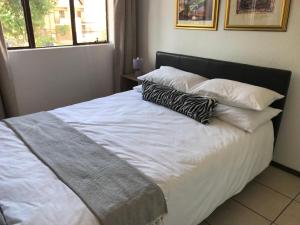 a bed with white sheets and pillows in a bedroom at Studio Eazi in Midrand