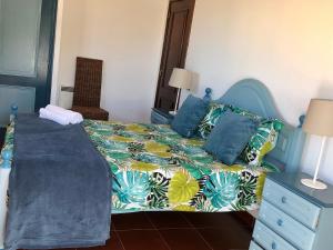 a bedroom with a bed with a colorful bedspread and pillows at Alojamento Santa Helena in A dos Cunhados