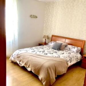 Schlafzimmer mit einem Bett mit einem Kopfteil aus Holz in der Unterkunft NUEVO! Con piscina a 2 minutos estación tren AVE. in Saragossa