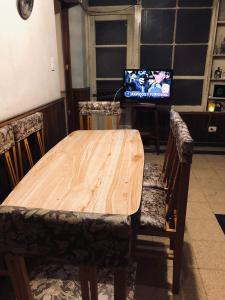 una mesa de madera y sillas con TV en una habitación en Casa Mirlo en Mendoza