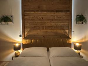 um quarto com uma cama com 2 candeeiros e uma parede de madeira em Apartmány Černý důl - Horňák em Černý Dŭl
