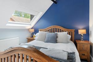 a bedroom with a wooden bed and a blue wall at Beautiful Secluded 2 Bedroom Coach House in Nottingham