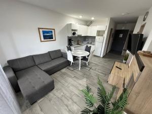 a living room with a couch and a table and a kitchen at Mifi Apartman Balatonlelle in Balatonlelle