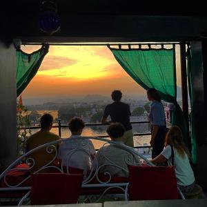 een groep mensen die vanuit een toren naar de zonsondergang kijken bij Tamasha Udaipur in Udaipur