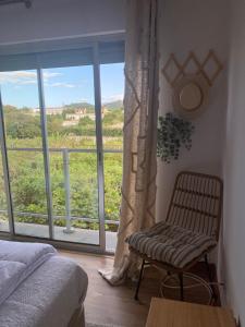 a bedroom with a chair and a large window at Apartamento Raposo in São Roque