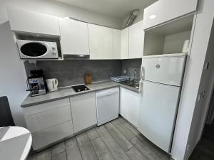 a kitchen with white cabinets and a white refrigerator at Mifi Apartman Balatonlelle in Balatonlelle
