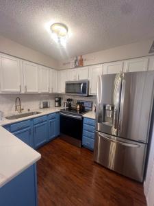 a kitchen with blue cabinets and a stainless steel refrigerator at Spacious Corporate Condo - 2bd/2ba in Madison