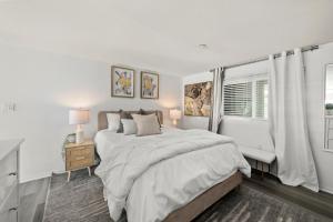 a white bedroom with a large bed and a window at The Italian Retreat, Little Italy in San Diego