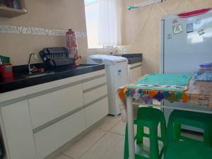 a kitchen with a sink and a table and a refrigerator at Apartamento inteiro próximo aeroporto de Confins in Vespasiano