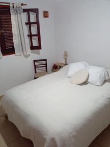 uma cama branca com almofadas brancas e uma janela em Casa en Punta Mogotes em Mar del Plata