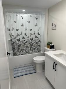 y baño con aseo y cortina de ducha. en Onyi’s cozy himalaya, en Hammonds Plains