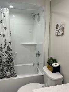 a white bathroom with a toilet and a shower at Onyi’s cozy himalaya in Hammonds Plains