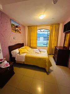 Schlafzimmer mit einem Bett und einem Fenster mit gelben Vorhängen in der Unterkunft Hostal Grand Rio in Baños