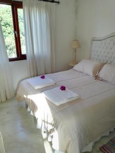 Una cama blanca con flores moradas encima. en Cabañas Boutique San Lorenzo en San Lorenzo