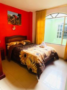 a bedroom with a bed with red walls and a window at Hostal Grand Rio in Baños