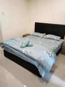 a bed with a blue comforter and pillows on it at Kuching Kozi Square Apartment III in Kuching