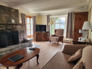 a living room with a couch and a fireplace at Auberge des Nuages in La Malbaie