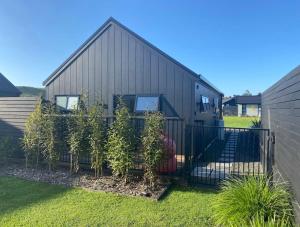 uma casa negra com árvores em frente em Private by the beach em Whitianga