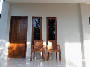 dwa krzesła siedzące przed drzwiami w obiekcie WL GUESTHOUSE w Labuan Bajo