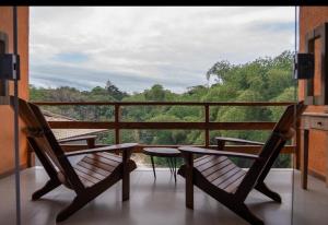 two chairs on a balcony with a view of trees at LOFT café da manhã e piscina ! in Trancoso