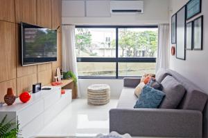 a living room with a couch and a large window at Apartamento Aconchegante Beira-Mar Ondina in Salvador