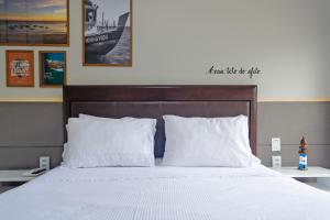 1 dormitorio con 1 cama con sábanas y almohadas blancas en Apartamento Aconchegante Beira-Mar Ondina, en Salvador