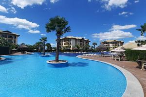 uma piscina num resort com uma palmeira no meio em VG Sun Cumbuco 4 Pessoas Nascente WiFi em Cumbuco