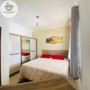 een slaapkamer met een bed met rode kussens bij Hospedagem Praia Central in Navegantes