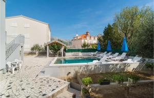 einen Pool mit Stühlen und blauen Sonnenschirmen in der Unterkunft Beautiful Apartment In Split With Wi-fi in Split