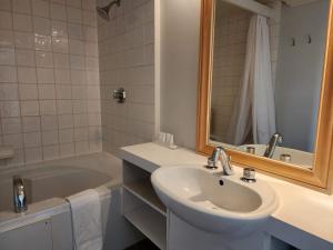 a bathroom with a sink and a mirror and a tub at Auberge des Nuages in La Malbaie