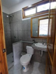 a bathroom with a toilet and a sink and a window at Wipeout Cabaña Restaurant in Las Tunas