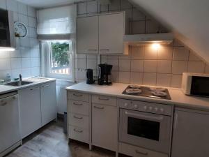 cocina con armarios blancos y fogones en Holiday apartment Stern in the heart of the Harz, en Wildemann