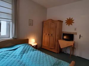 a bedroom with a bed and a cabinet and a television at Holiday apartment veranda in the heart of the Harz in Wildemann