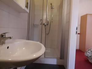 a white bathroom with a shower and a sink at Holiday apartment veranda in the heart of the Harz in Wildemann