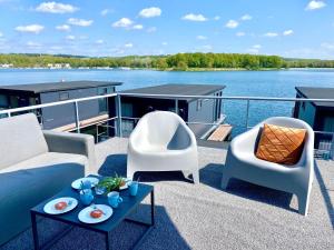 uma varanda com 2 cadeiras e um sofá num barco em Luxury houseboat with roof terrace and beautiful view over the Mookerplas em Middelaar