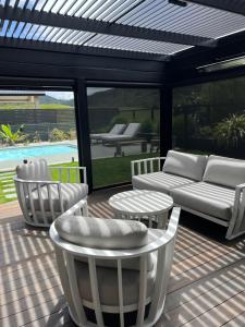 un patio avec des chaises, un canapé et une table dans l'établissement Paradise by Simpsons beach, à Whitianga