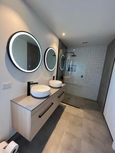 une salle de bain avec deux lavabos et un grand miroir dans l'établissement Paradise by Simpsons beach, à Whitianga 4 autres photos