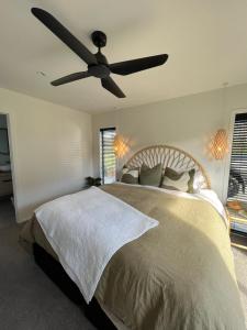 une chambre avec un lit avec un ventilateur de plafond dans l'établissement Paradise by Simpsons beach, à Whitianga