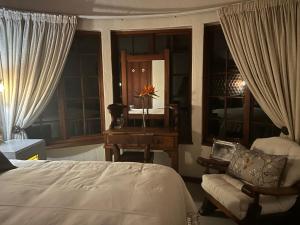 Schlafzimmer mit einem Bett, einem Schreibtisch und einem Spiegel in der Unterkunft Oak Tree Lodge, Beaulieu, Kyalami in Midrand