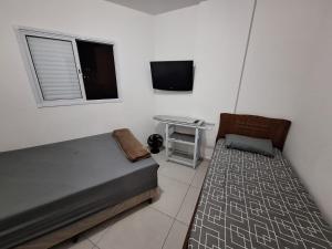 a bedroom with a bed and a table and a tv at Fermont 32 in Praia Grande