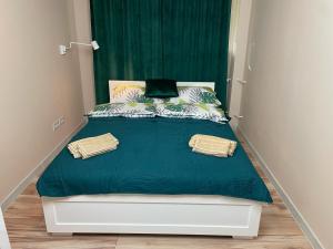 Cama en habitación pequeña con cortinas verdes en Apartament Komfortowy z Widokiem, en Toruń