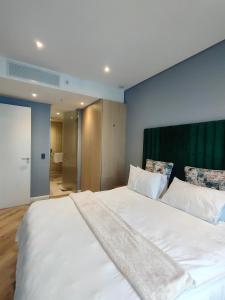 a bedroom with a large white bed with a green headboard at Modern 1BR APT Near Sandton City No Loadshedding in Johannesburg